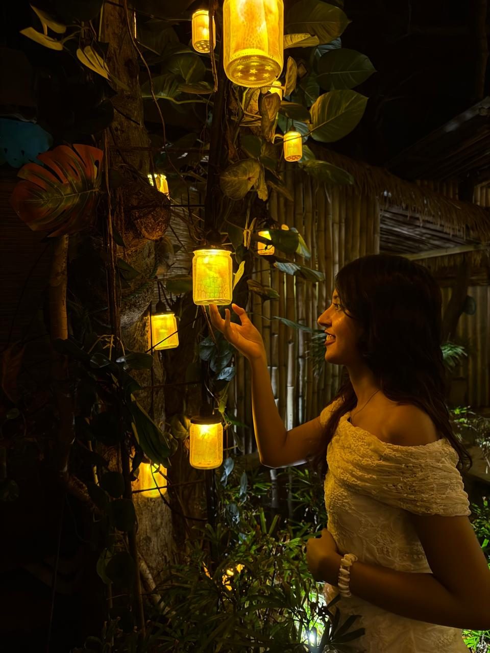 Treya reaching toward warm hanging lanterns