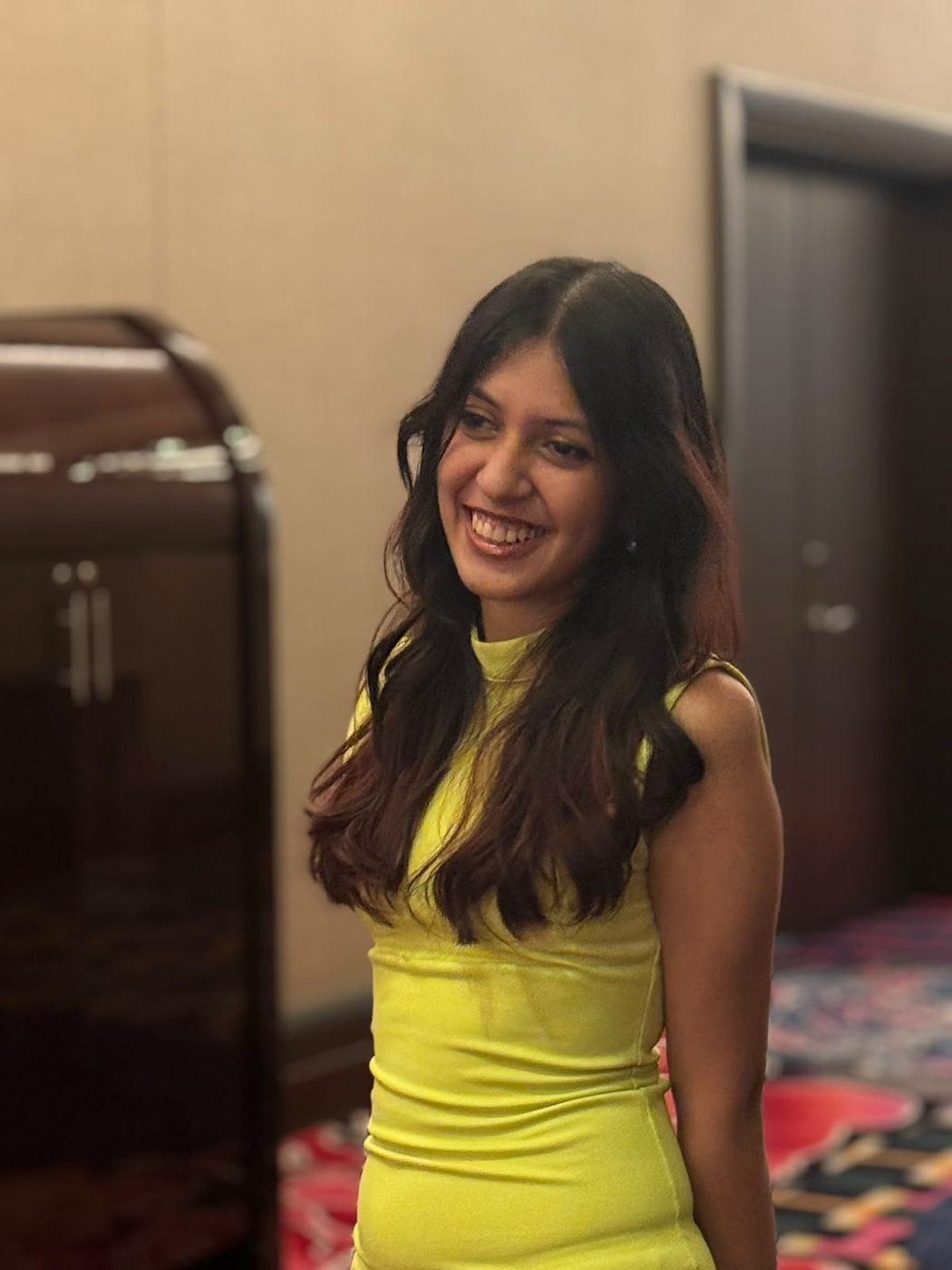 Treya, smiling, in a warm yellow dress